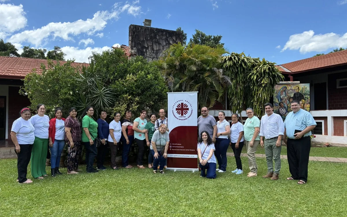 Equipo de la Pastoral del Niño reunido junto al banner de la Pastoral Social Cáritas Paraguay